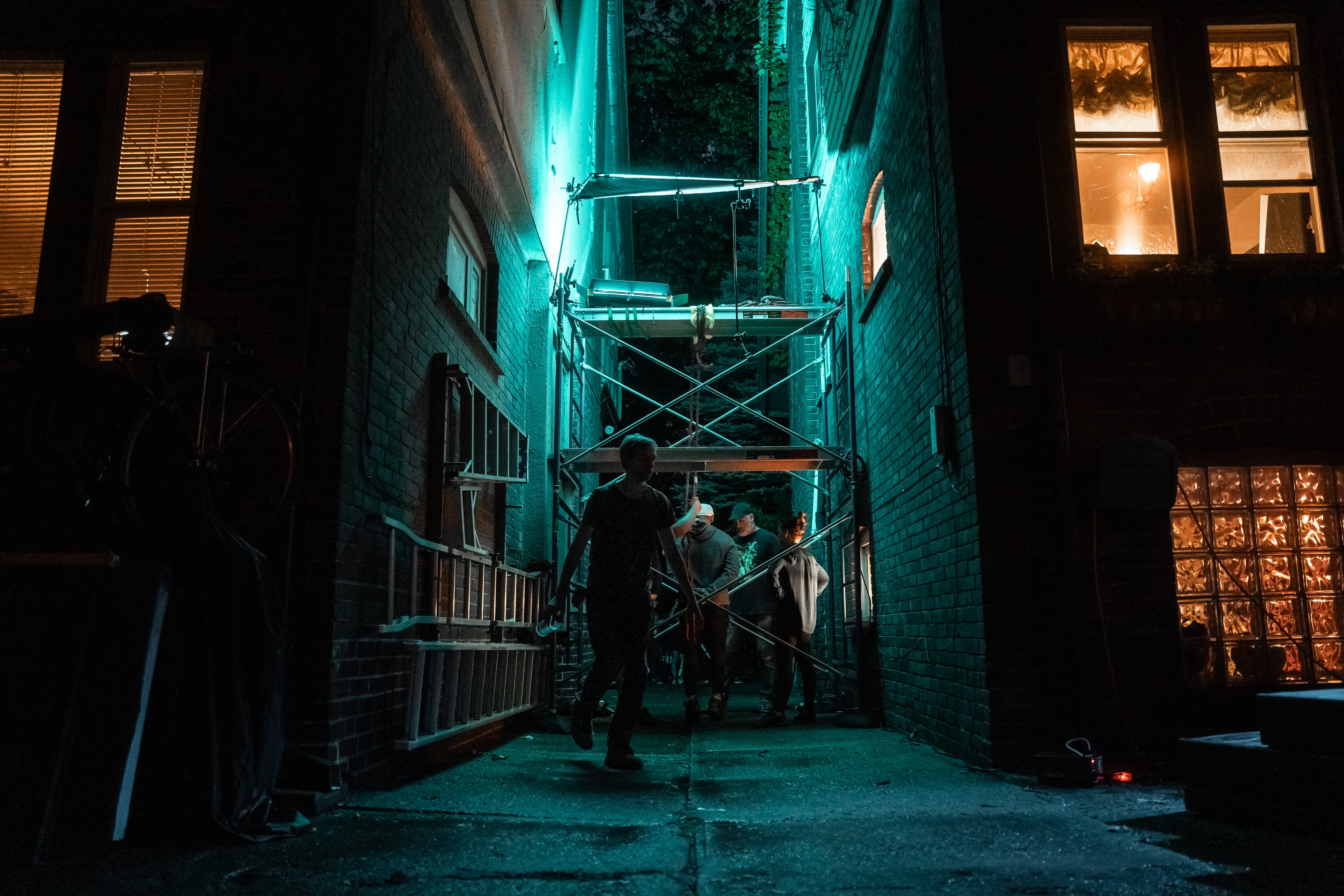 Behind the scenes — crew setting up in alley with neon cyan lighting